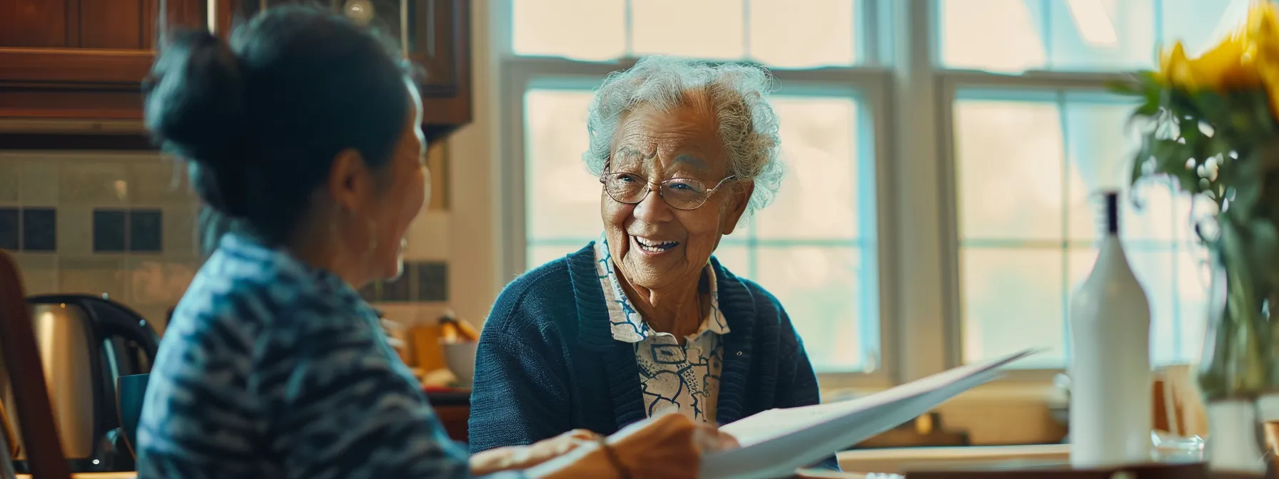 a smiling elderly person sitting at a kitchen table, reviewing paperwork with a professional caregiver from a reputable personal care agency.